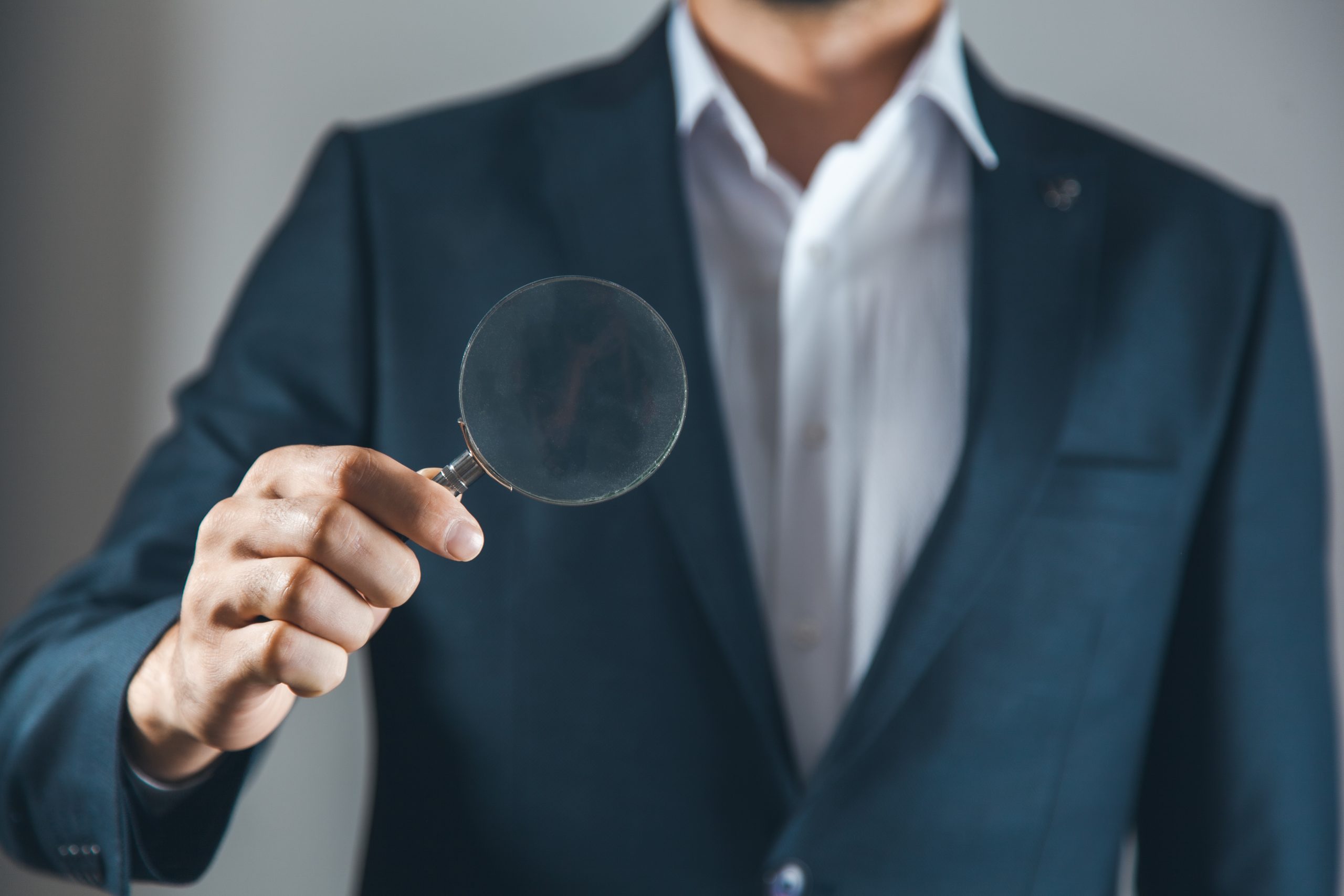 Człowiek z lupą szukający odpowiednią firmę od SEO.